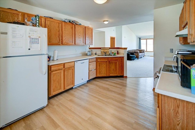 kitchen featuring a sink, under cabinet range hood, white appliances, a peninsula, and light countertops