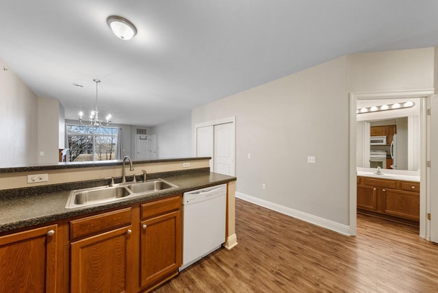 kitchen with white appliances, dark countertops, a sink, and brown cabinets