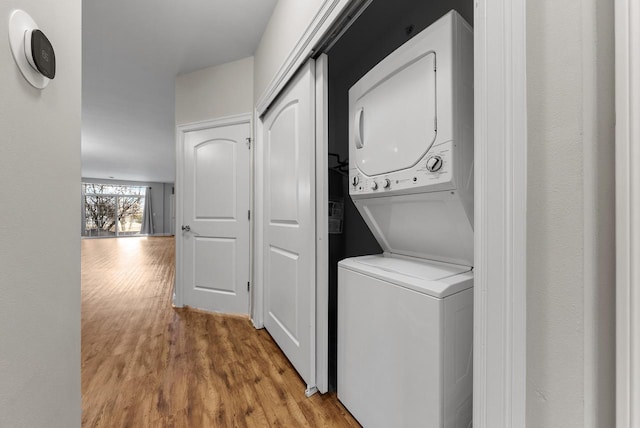 laundry area with stacked washer and dryer, wood finished floors, and laundry area