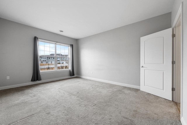 carpeted empty room featuring baseboards