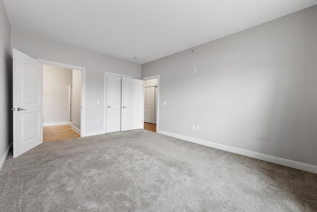 unfurnished bedroom featuring carpet, a closet, and baseboards