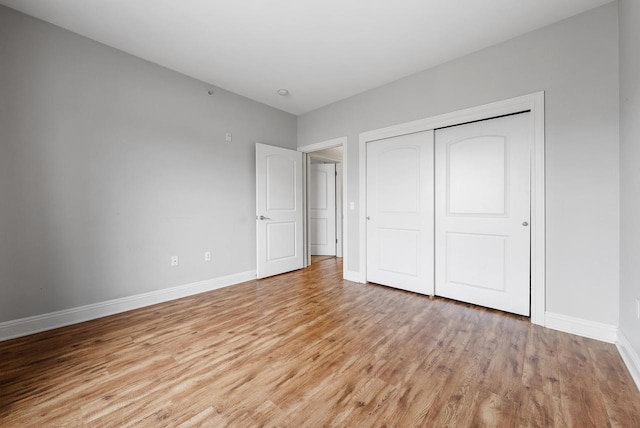 unfurnished bedroom with a closet, light wood-style flooring, and baseboards