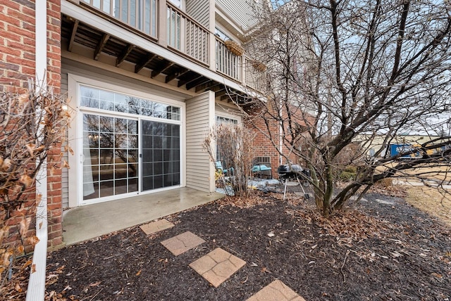 view of side of home featuring brick siding and a balcony