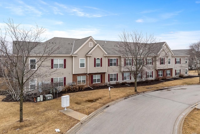 townhome / multi-family property with a residential view, brick siding, and a front lawn