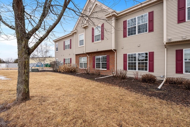 multi unit property featuring a front lawn and brick siding