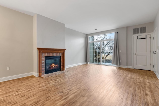 unfurnished living room with baseboards, a fireplace, visible vents, and wood finished floors