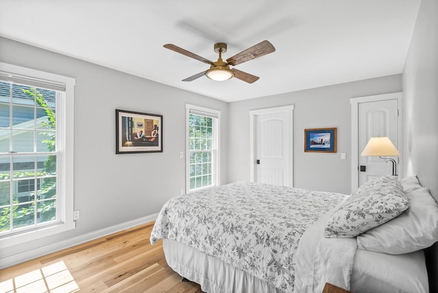 bedroom with a ceiling fan, light wood-style flooring, and baseboards