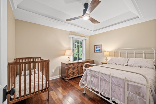 bedroom featuring a ceiling fan, a tray ceiling, dark wood finished floors, and baseboards