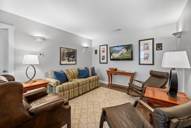 living area with baseboards, visible vents, and wood finished floors