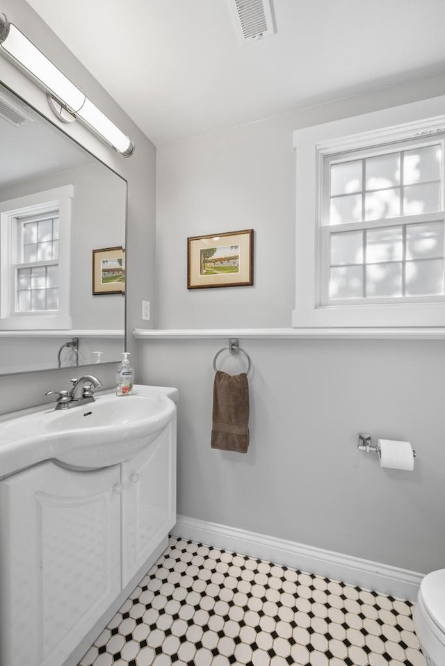 half bathroom featuring baseboards, visible vents, toilet, and tile patterned floors