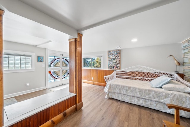 bedroom featuring baseboards, wood finished floors, and ornate columns