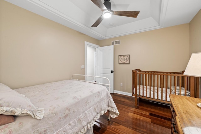 bedroom featuring wood finished floors, a ceiling fan, visible vents, baseboards, and a raised ceiling