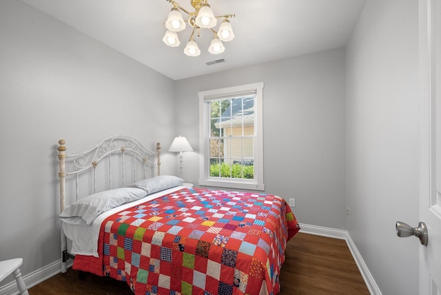 bedroom featuring a notable chandelier, wood finished floors, visible vents, and baseboards