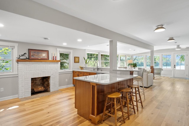 kitchen featuring open floor plan, a breakfast bar area, a brick fireplace, and light wood-style floors