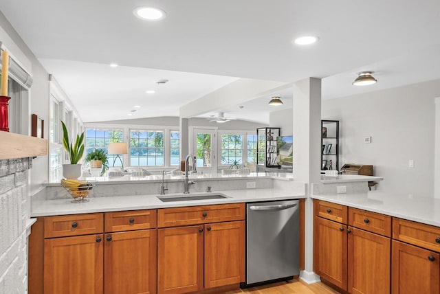 kitchen with vaulted ceiling, light countertops, a sink, and stainless steel dishwasher