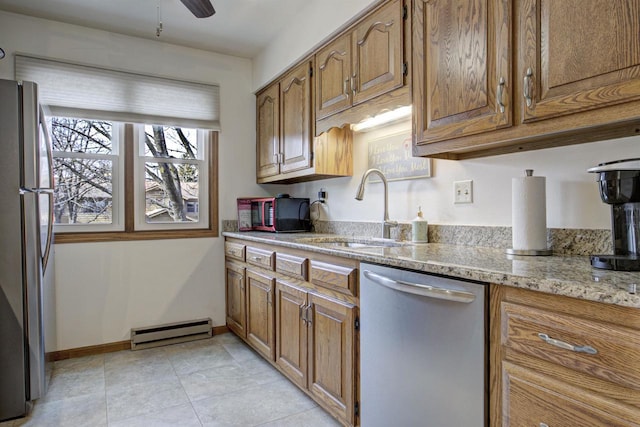 kitchen with stainless steel appliances, baseboard heating, a sink, and brown cabinets