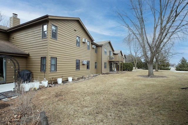 view of side of property featuring a shingled roof and a chimney