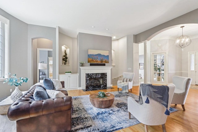 living room featuring arched walkways, a high end fireplace, and light wood-style floors