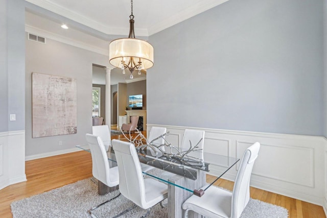 dining space featuring a wainscoted wall, visible vents, a fireplace, and wood finished floors