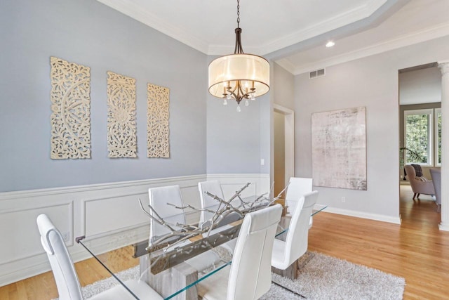 dining room with visible vents, a wainscoted wall, wood finished floors, an inviting chandelier, and crown molding