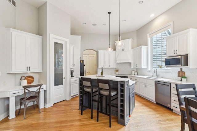 kitchen featuring stainless steel appliances, a breakfast bar, a sink, and white cabinetry