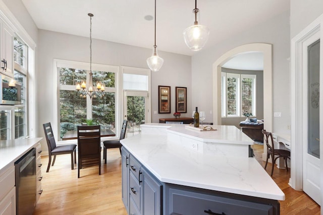 kitchen with dishwasher, light wood finished floors, a kitchen island, and decorative light fixtures