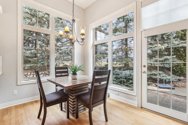 dining room with a notable chandelier, baseboards, and light wood-style floors