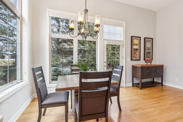 dining area with light wood-style floors, a notable chandelier, and baseboards