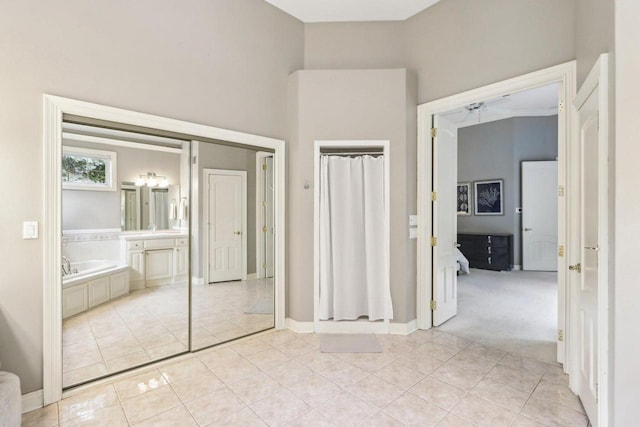 unfurnished bedroom featuring light colored carpet, light tile patterned flooring, ensuite bath, and a high ceiling