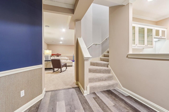 staircase featuring ornamental molding, baseboards, and wood finished floors