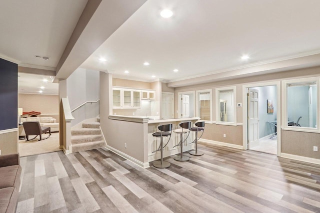 kitchen with light wood-type flooring, white cabinets, a kitchen breakfast bar, and recessed lighting