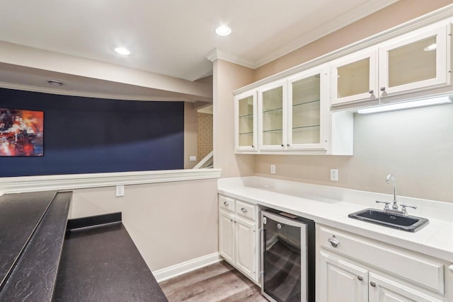 kitchen featuring beverage cooler, a sink, white cabinetry, light countertops, and glass insert cabinets