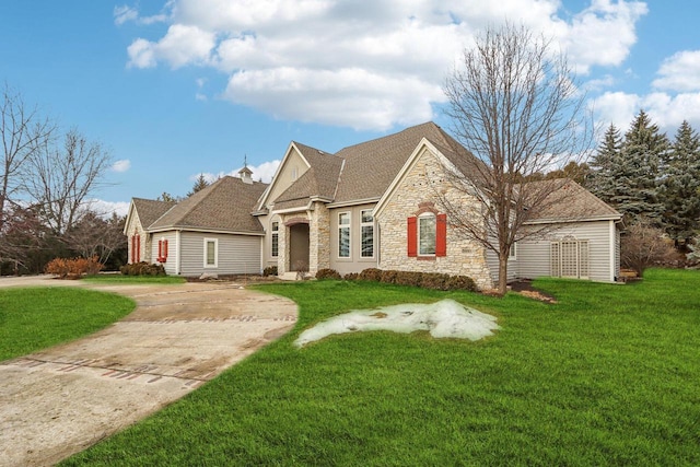 french provincial home featuring a front yard, stone siding, and concrete driveway