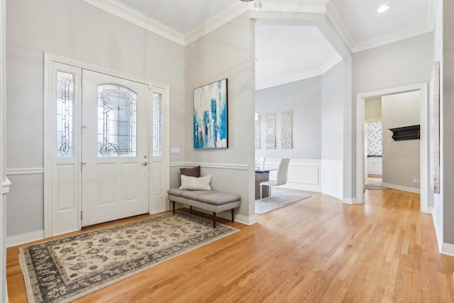 entryway with a wainscoted wall, crown molding, a decorative wall, and wood finished floors