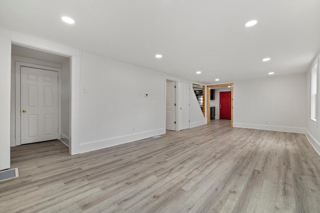 empty room with light wood-style floors, recessed lighting, visible vents, and stairway