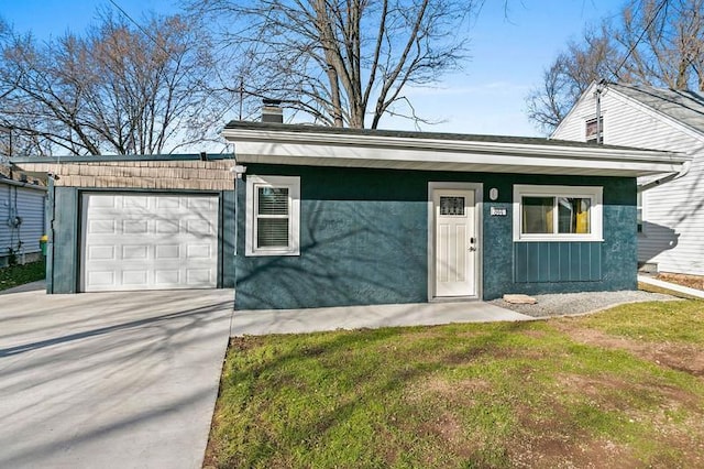 view of front facade with a chimney, an attached garage, board and batten siding, a front yard, and driveway