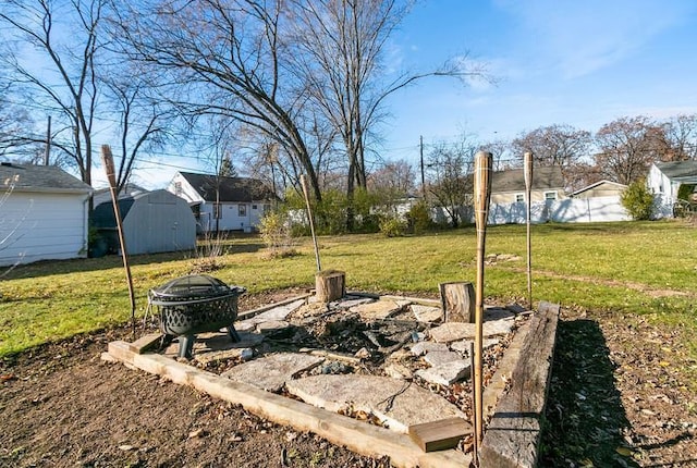 view of yard with an outdoor structure, a fire pit, and a shed