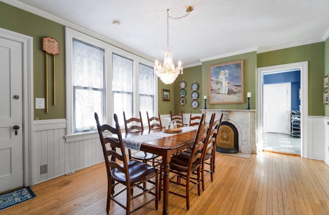 205 State St, Ripon, WI 54971 - dining space with light wood-style floors, crown molding, a wainscoted wall, and an inviting chandelier