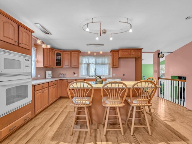 kitchen featuring light wood-type flooring, white appliances, light countertops, and a kitchen island