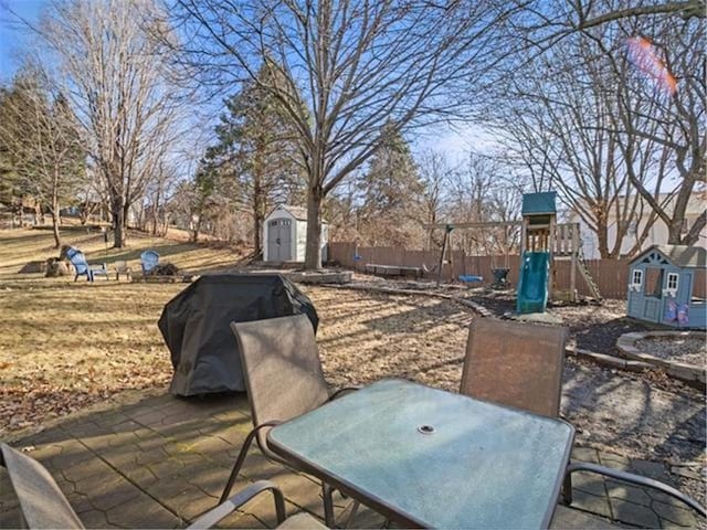 view of patio featuring area for grilling, an outbuilding, fence, a shed, and outdoor dining space