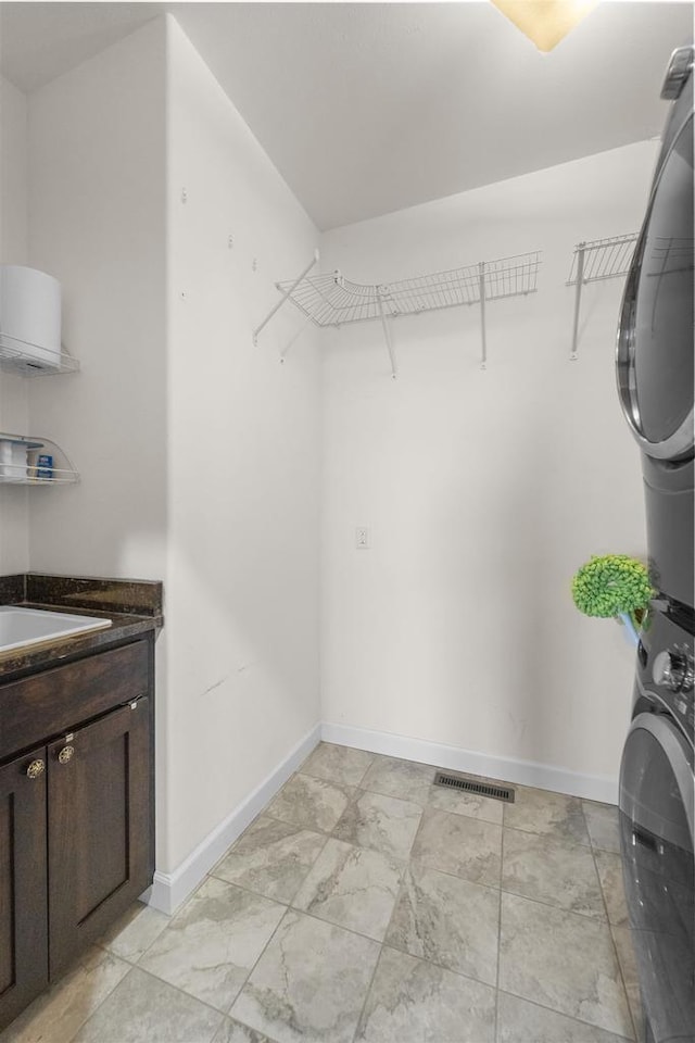 spacious closet featuring stacked washer and clothes dryer, visible vents, and a sink