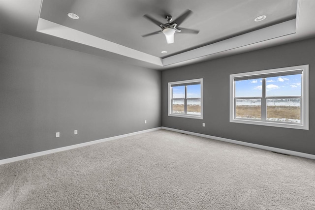 empty room with a tray ceiling, carpet, baseboards, and recessed lighting