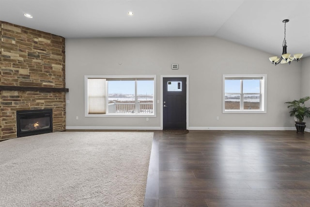 unfurnished living room with a large fireplace, a notable chandelier, lofted ceiling, and a healthy amount of sunlight