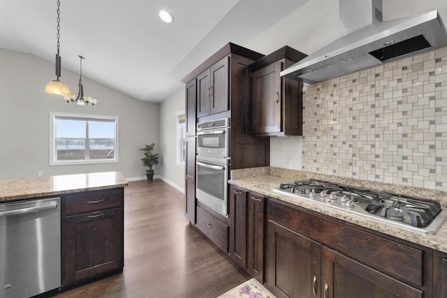 kitchen featuring stainless steel appliances, lofted ceiling, decorative backsplash, dark brown cabinetry, and wall chimney range hood