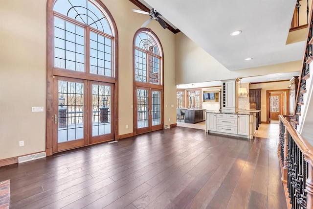 unfurnished living room featuring baseboards, visible vents, dark wood-type flooring, a high ceiling, and french doors