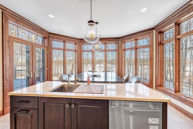 kitchen featuring a kitchen island with sink, a sink, light countertops, dishwasher, and decorative light fixtures