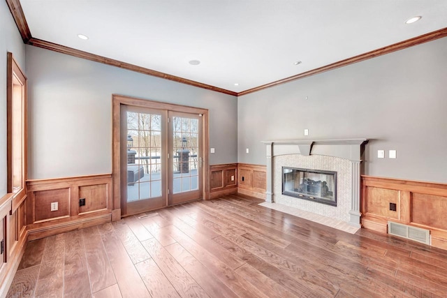 unfurnished living room featuring recessed lighting, visible vents, a fireplace with flush hearth, wainscoting, and wood finished floors