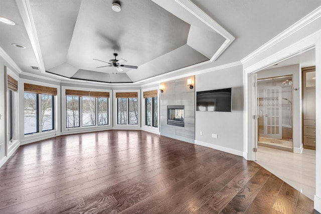 unfurnished living room with a raised ceiling, crown molding, and wood-type flooring