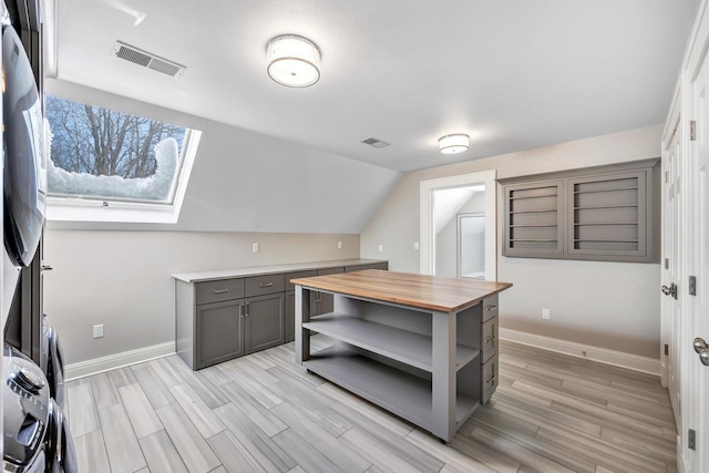 interior space featuring vaulted ceiling, wood finish floors, visible vents, and baseboards