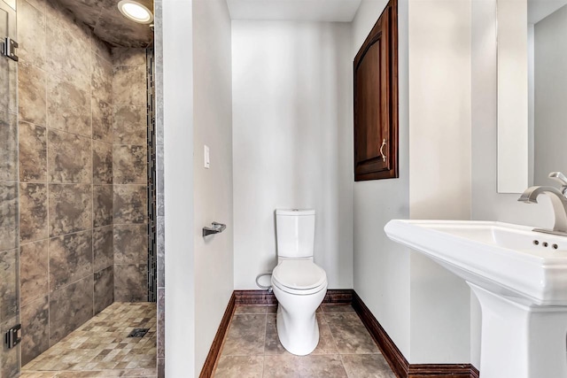 full bathroom featuring baseboards, a sink, a shower stall, and toilet